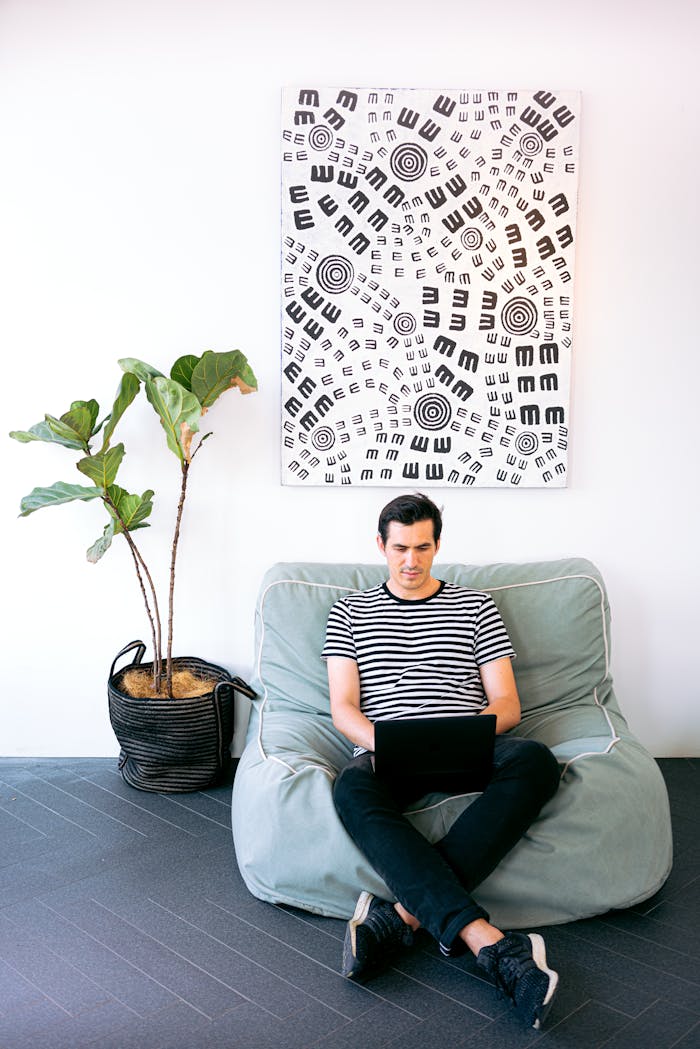 Young man working on laptop in stylish home office setting with modern decor.